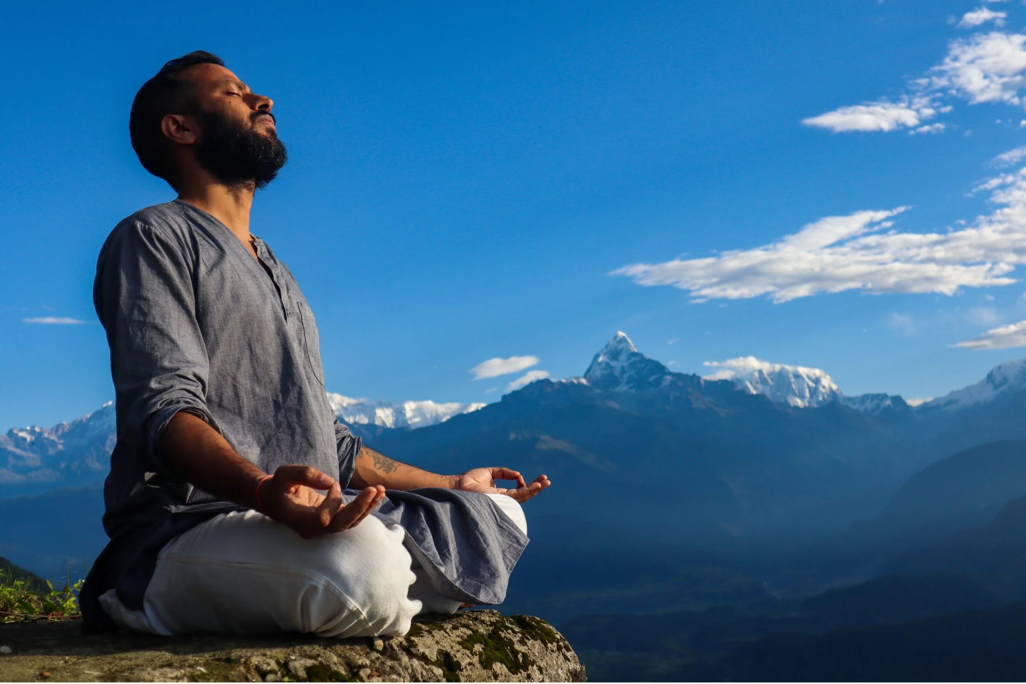 A man doing mediation in Pokhara surrounded by mountains