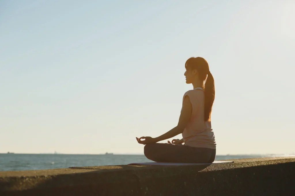 A woman meditating in peaceful near ocean in the morning