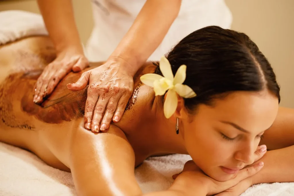A women getting body scrub massage with the use of herbal product to maximize the benefits of body scrub massage.